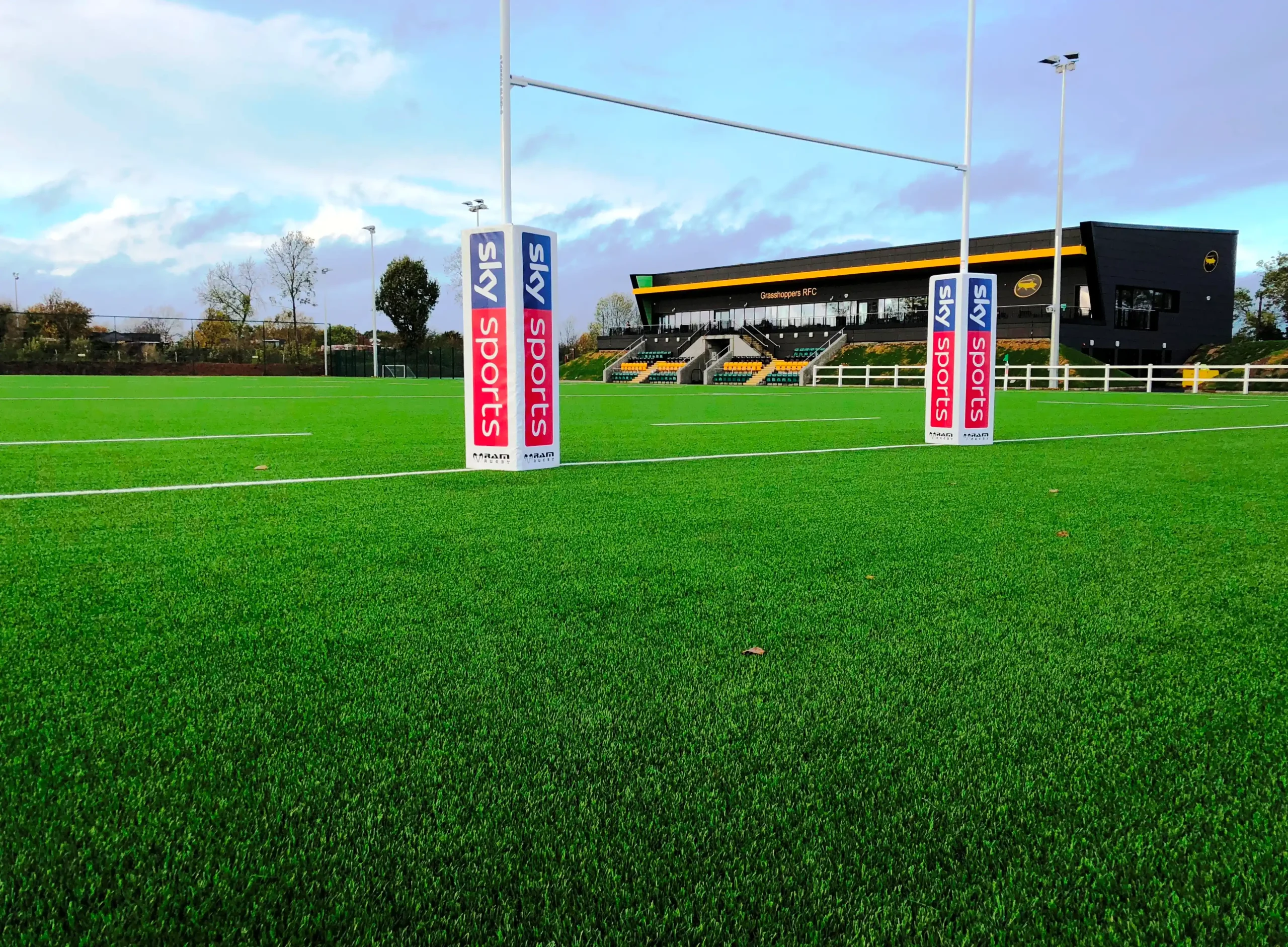 Large green field at the Grasshopper RFC with rugby goal line and Sky Sports banners.